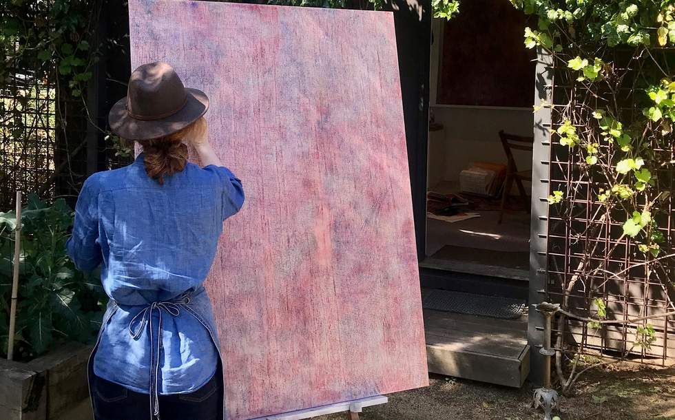 An artist working outdoors on a large canvas from an easel. 