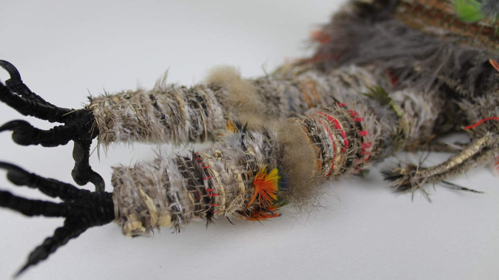 Close up photo of the legs of a woven sculpture made of natural fibres.