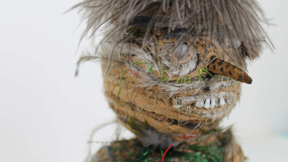 Close up photo of the head of a woven sculpture made from natural fibres.
