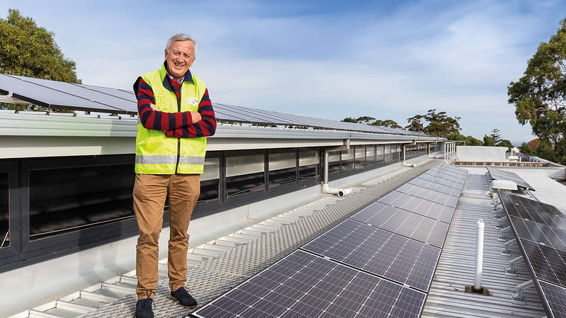 Bayside Mayor Cr Laurence Evans standing at rooftop solar panels on a council building