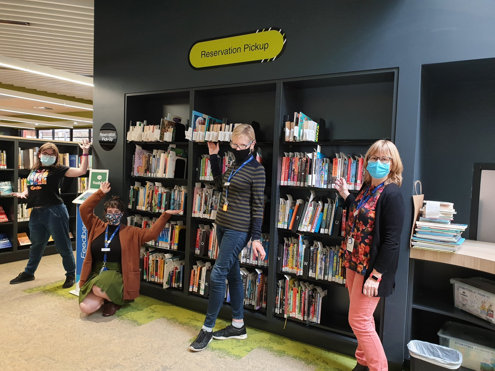 Library staff wearing masks in front of a book case