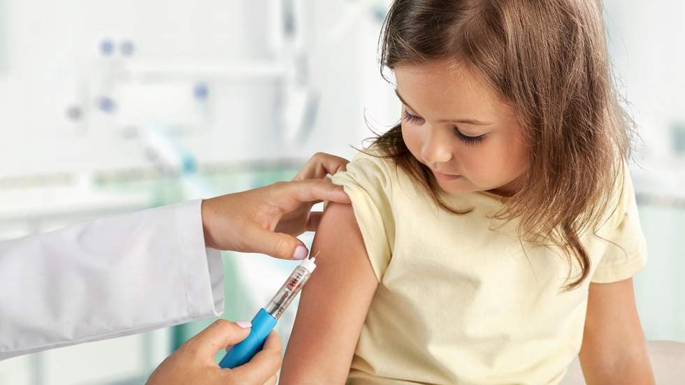 Little girl receiving a flu shot in her arm.