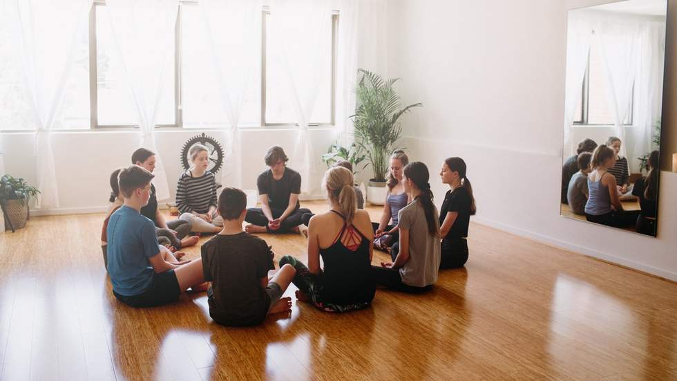 Circle of teens practicing meditation in a room