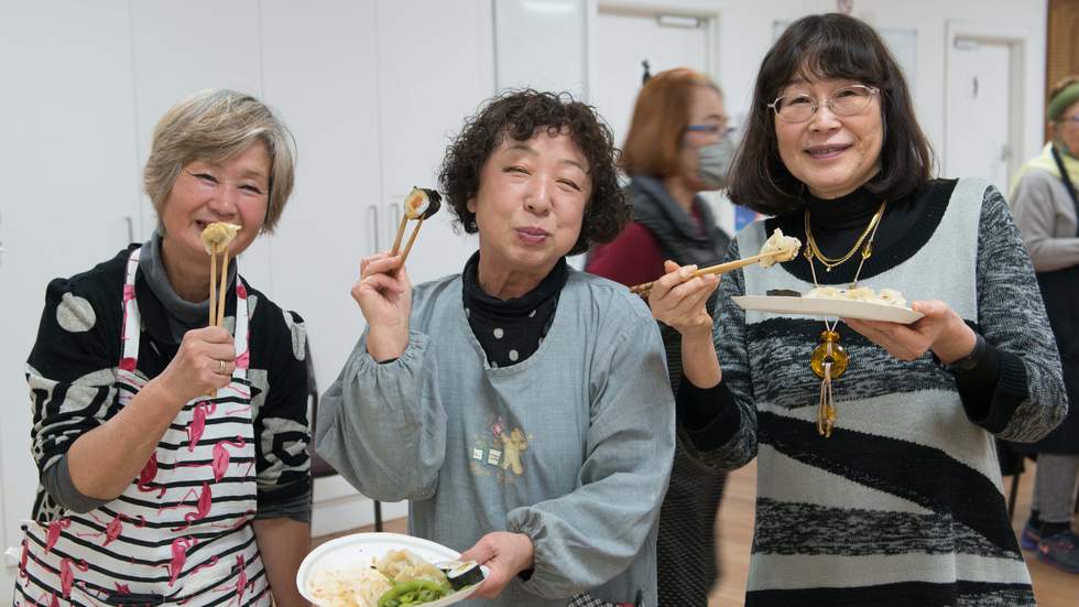Photograph of three women eating Japanese food smiling at the camera