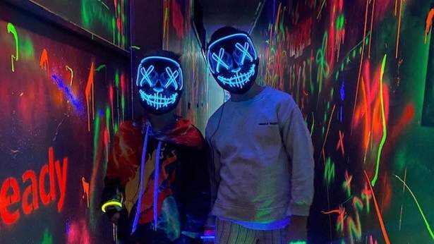 Photograph of two people with neon lights on, wearing face masks