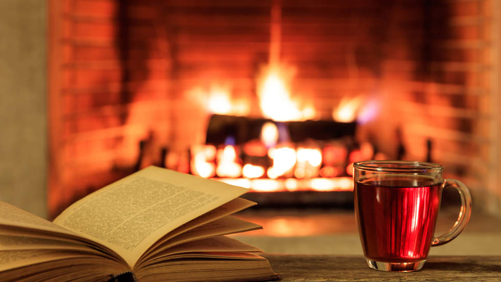 Open book with tea in front of fireplace