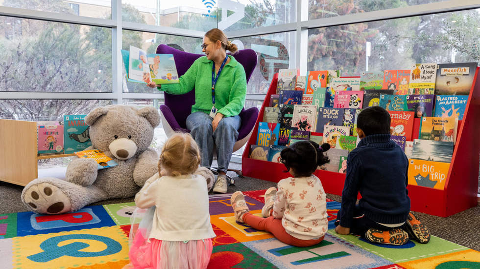Librarian reading a children's book to kids during a storytime session at the library