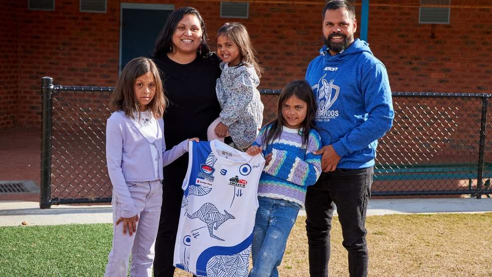 Artist and her family proudly holding an AFL jersey with her design on it.