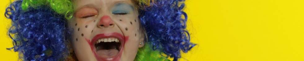 A child with colourful face painting and a colourful wig