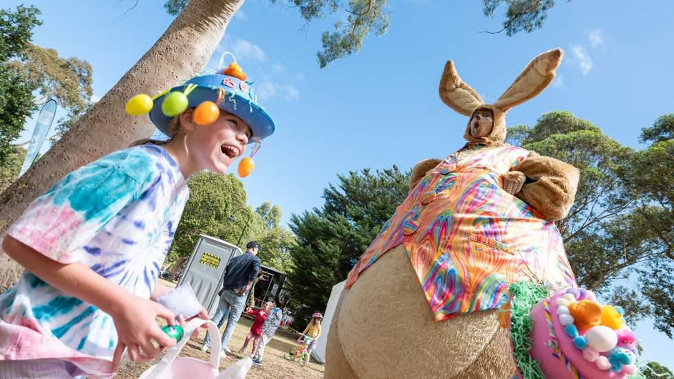 Child laughing with giant bunny at Easter event.