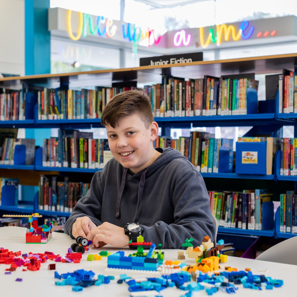 A boy playing with LEGO at a library