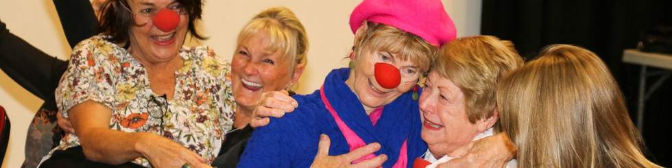 Group of senior citizens smiling and wearing red noses