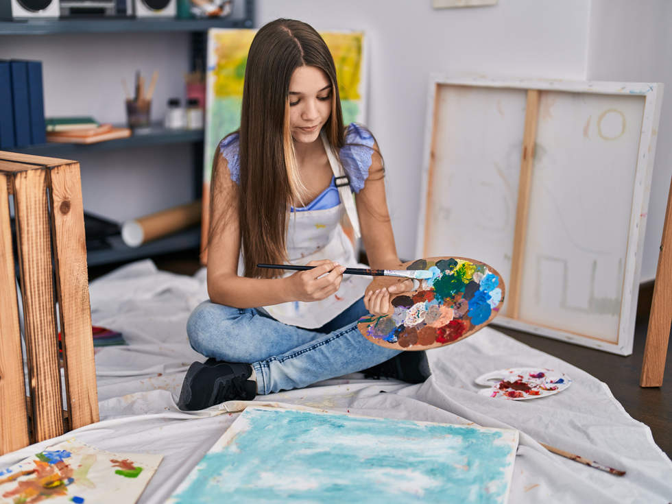 Young woman using painting palette to paint.