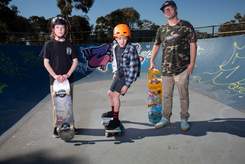 Two skateboarders watching another teenage boy skateboarding