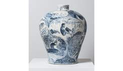 A large white ceramic vase decorated with blue illustrations of surfers.