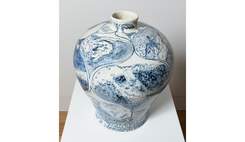 A large white ceramic vase, decorated with blue illustrations of surfers.