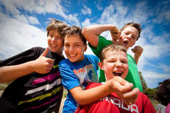 Group of boys wearing colorful t-shirts smiling and joking around