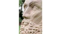 Close up view of a sculptured face of a bearded man made from sandstone. 