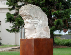 A side view of a sculptured head on a plinth in Billilla gardens.