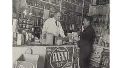 old black and white photo of man in grocery sop with boy