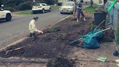 Teenagers digging up nature strip reading for planting