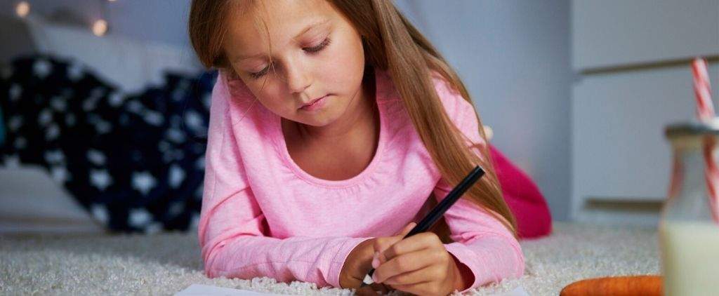 Young girl writing letter laying down.