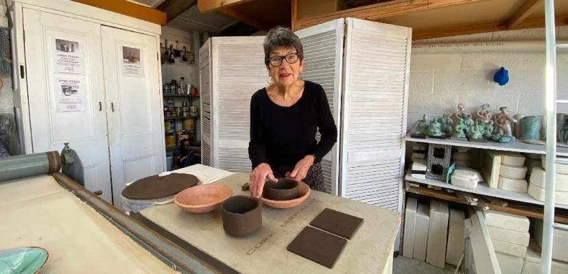 Jill Symes in her studio holding her ceramic pieces.