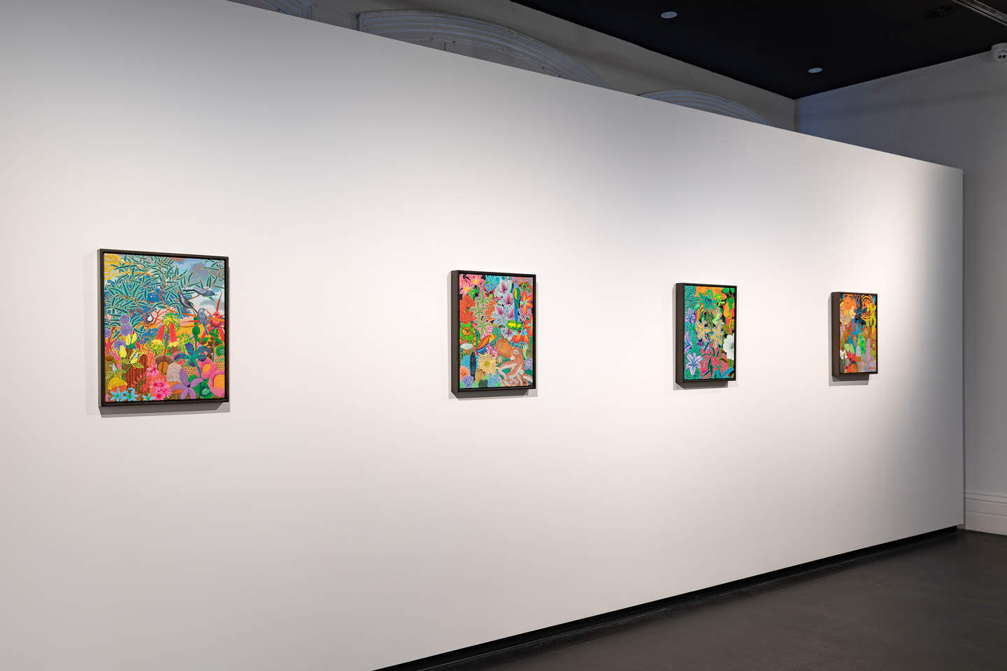 Interior photograph of a series of colourful paintings on a white wall