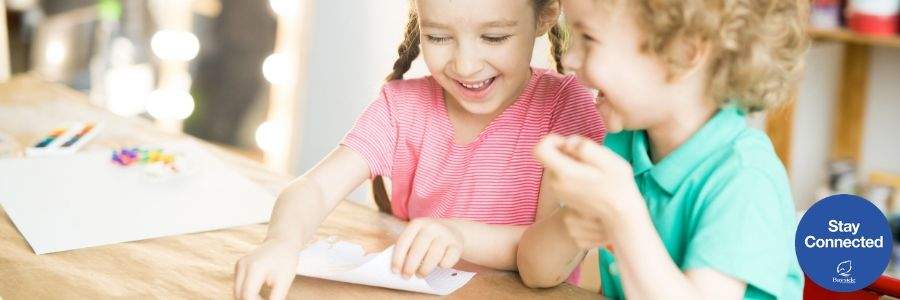 Two smiley kids writing a letter. 