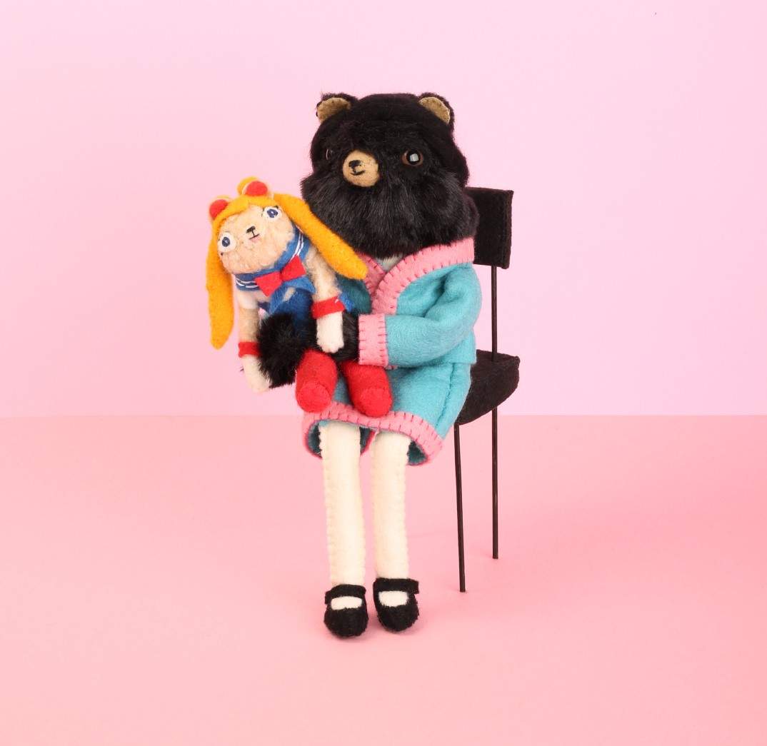 A seated bear holding a rag doll.