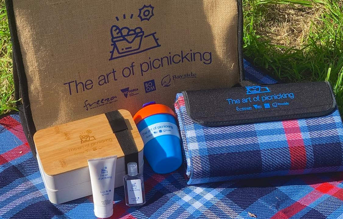 Picnic pack including tartan rug, lunchbox, keepcup, sunscreen and antibacterial gel.
