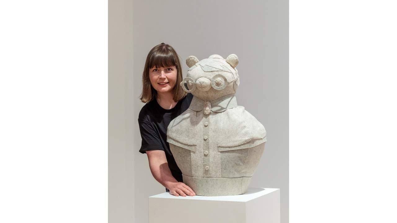 Artist Cat Rabbit poses with a white felted sculpture of a bear.