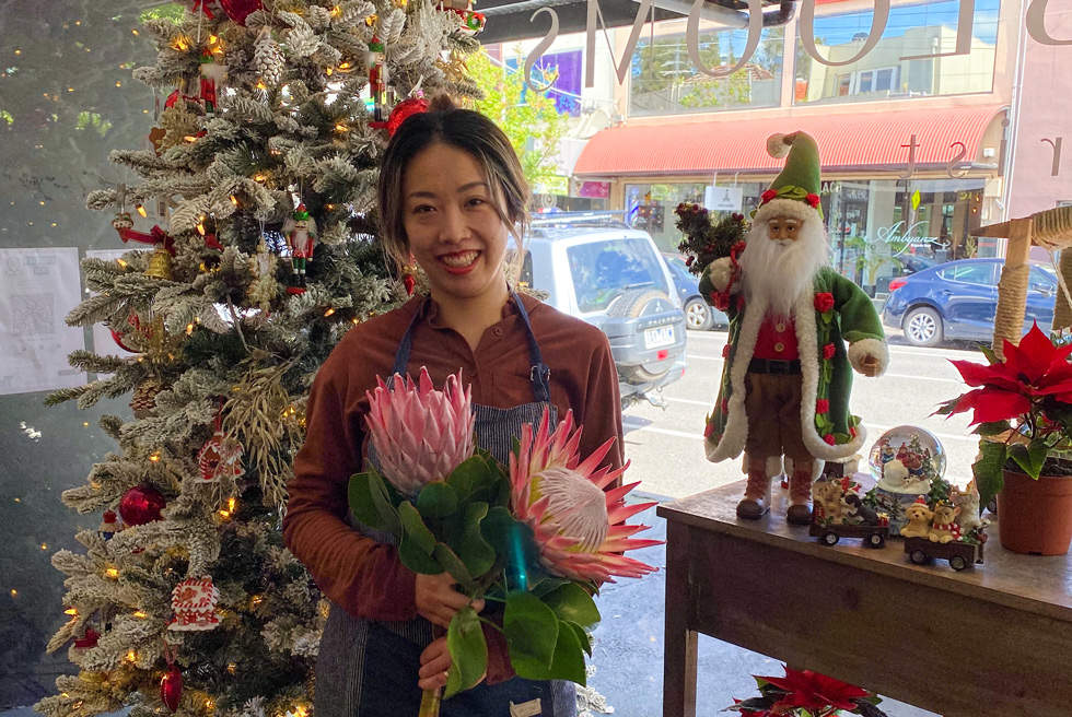 Florist store owner with Christmas tree, flowers at her festive window