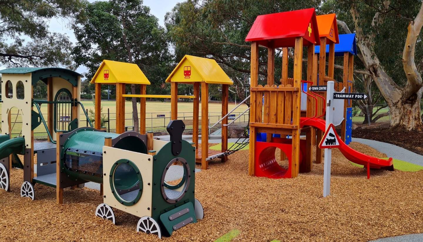 Banksia Playground showing train, slide, wobbly bridge, trees and mulch