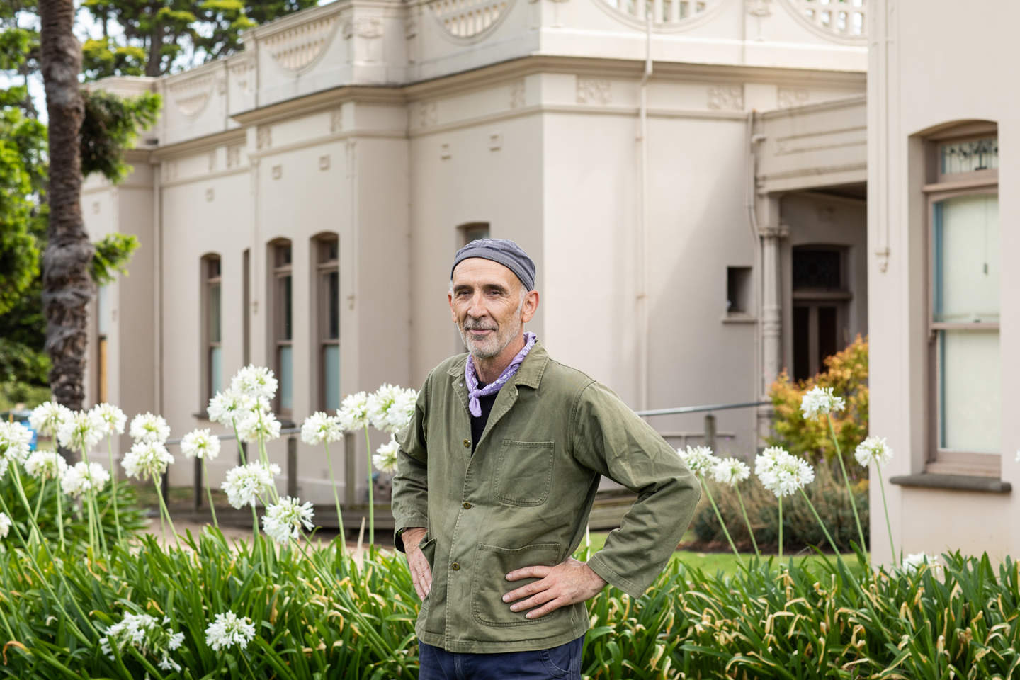 Artist Adrian Spurr poses towards the camera in the garden of Billilla House 