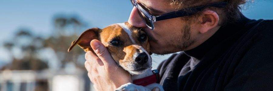 Man in sunglasses kissing his dog