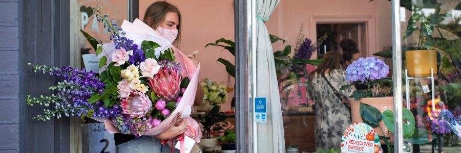 Woman walking out shop with huge bunch of flowers