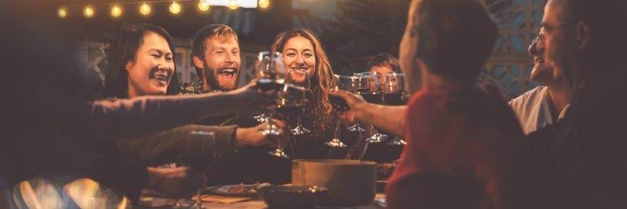 Group of friends at a restaurant garden clinking wine glasses