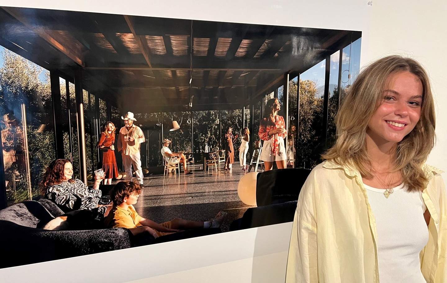 Student Rose King stands in front of her photograph of people at a party.