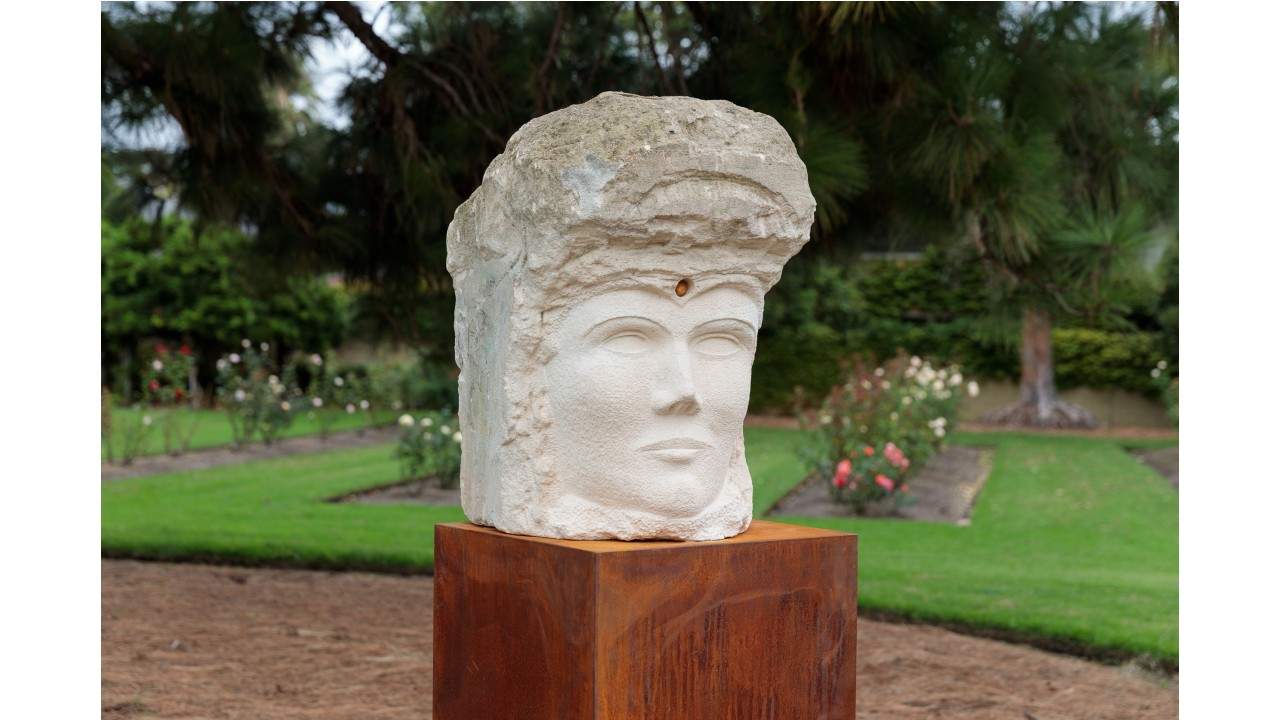 A limestone sculpture of a head on a plinth at Billilla gardens. 