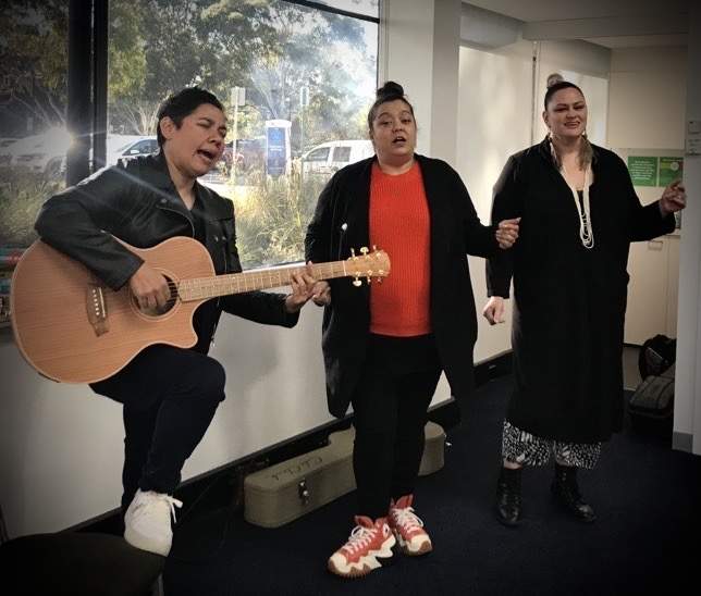 Three female performers from Jessie Lloyd Music Group singing, one is playing the guitar.