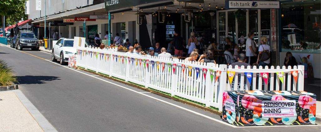 Outdoor dining parklet with white fence