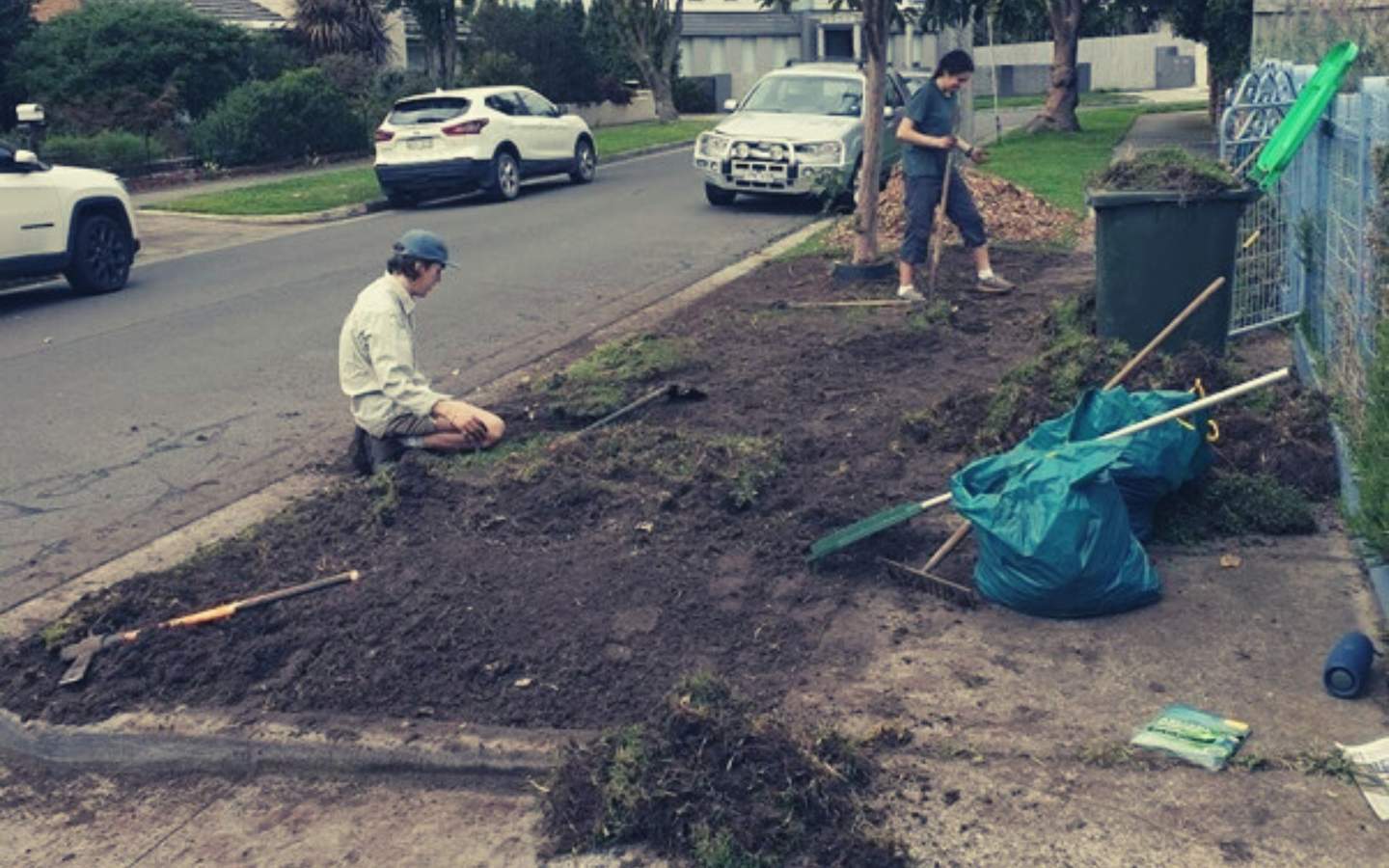 Teenagers digging up nature strip reading for planting