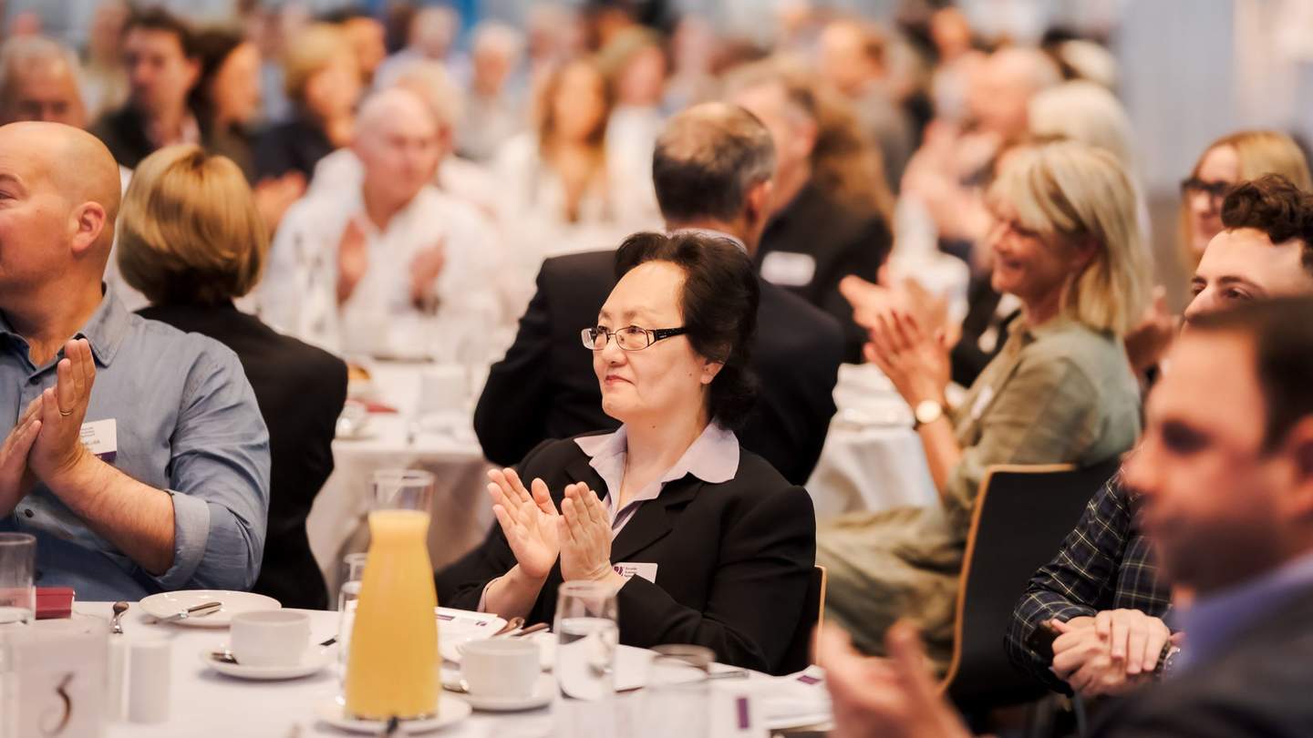 People at table clapping at business event