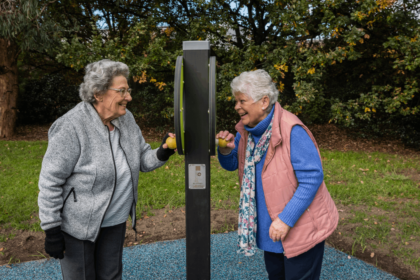 Maureen and Jackie look at each other through new healthy ageing exercise equipment in Tibrockney Street Park