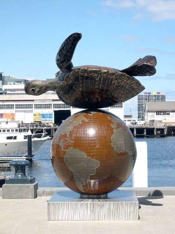 A brass sculpture of a turtle upside down on the earth