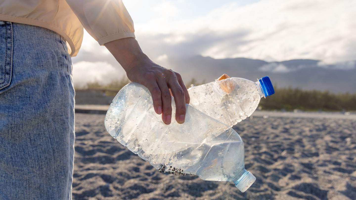 Hand holding plastic bottles on beach