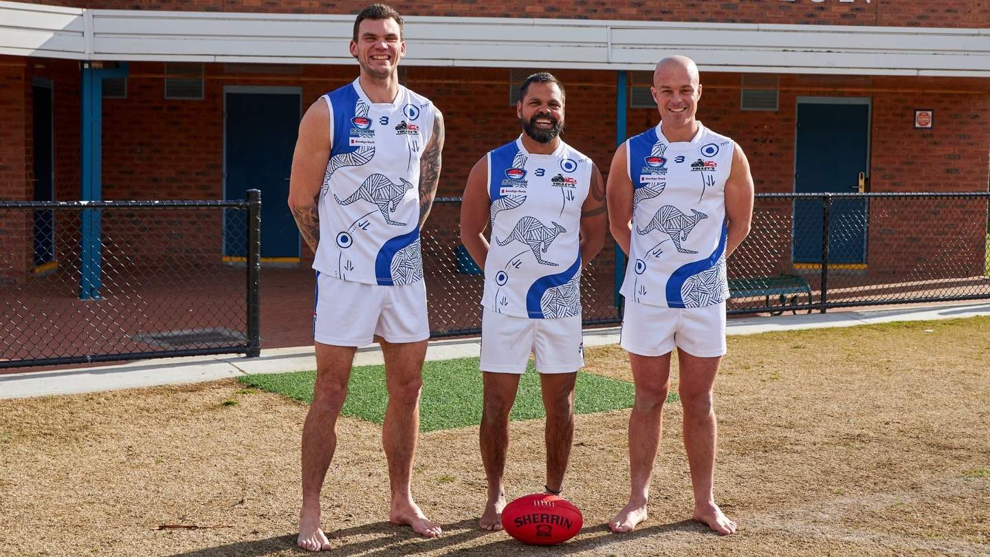 Three AFL players standing by the pavillion