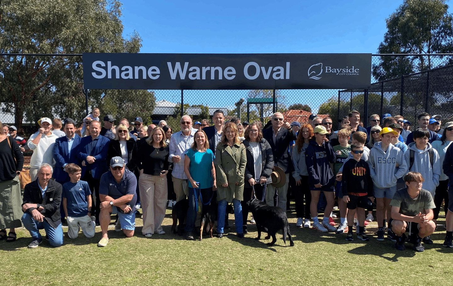 People standing in front of Shane Warne Oval sign