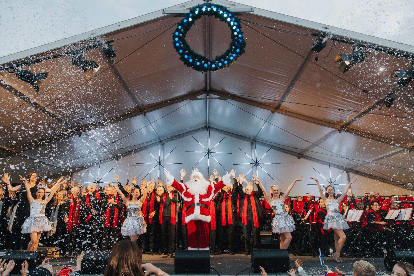 Carols image of Santa and choir standing on stage singing carols
